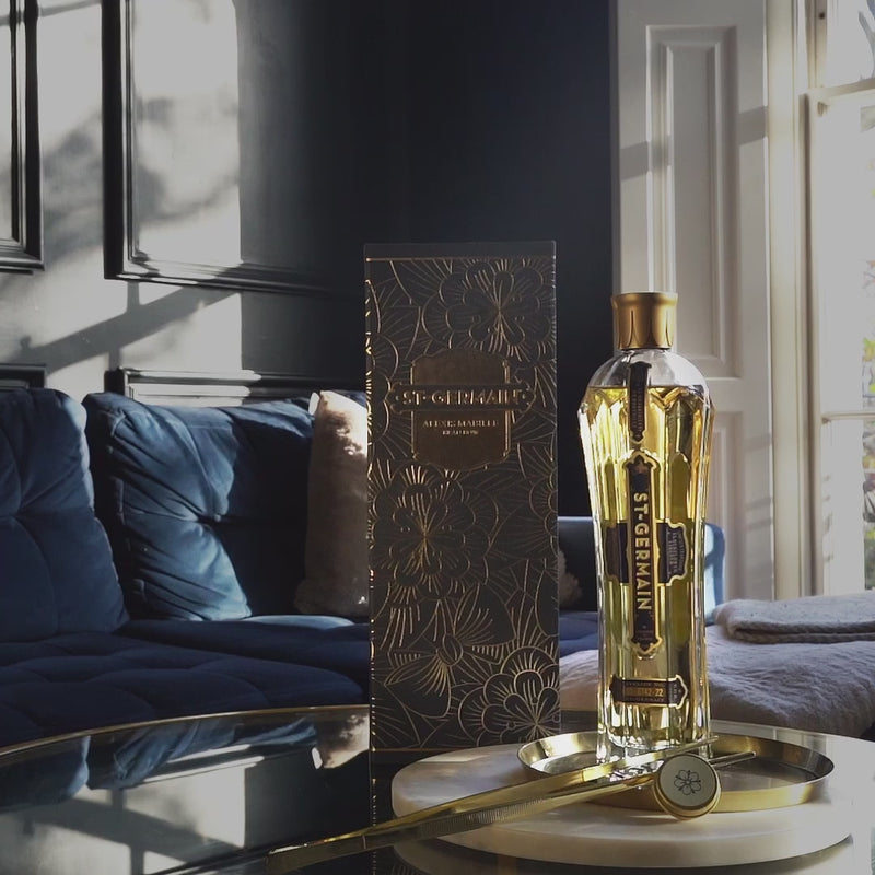 St-Germain x Alexis Mabille coffret édition limitée, comprenant une bouteille art déco, une bouteille de St-Germain, une grande pince à ingrédients dorée, une boîte renfermant des pétales d’or